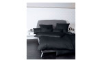 Mako-Satin Kissenbezug Colors in der Größe 40 x 80 cm und in der Farbausführung schwarz, auf einem Bett bezogen mit der passenden Bettwäsche und weiteren Kissen